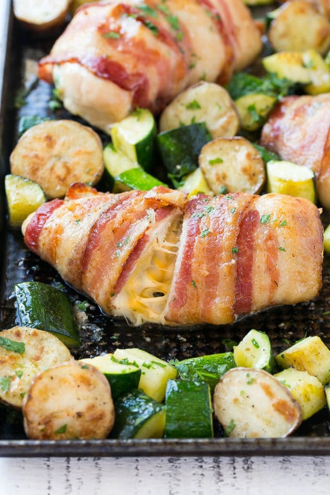 This recipe for bacon wrapped stuffed chicken breast with roasted potatoes and zucchini is a quick and easy one pan meal that