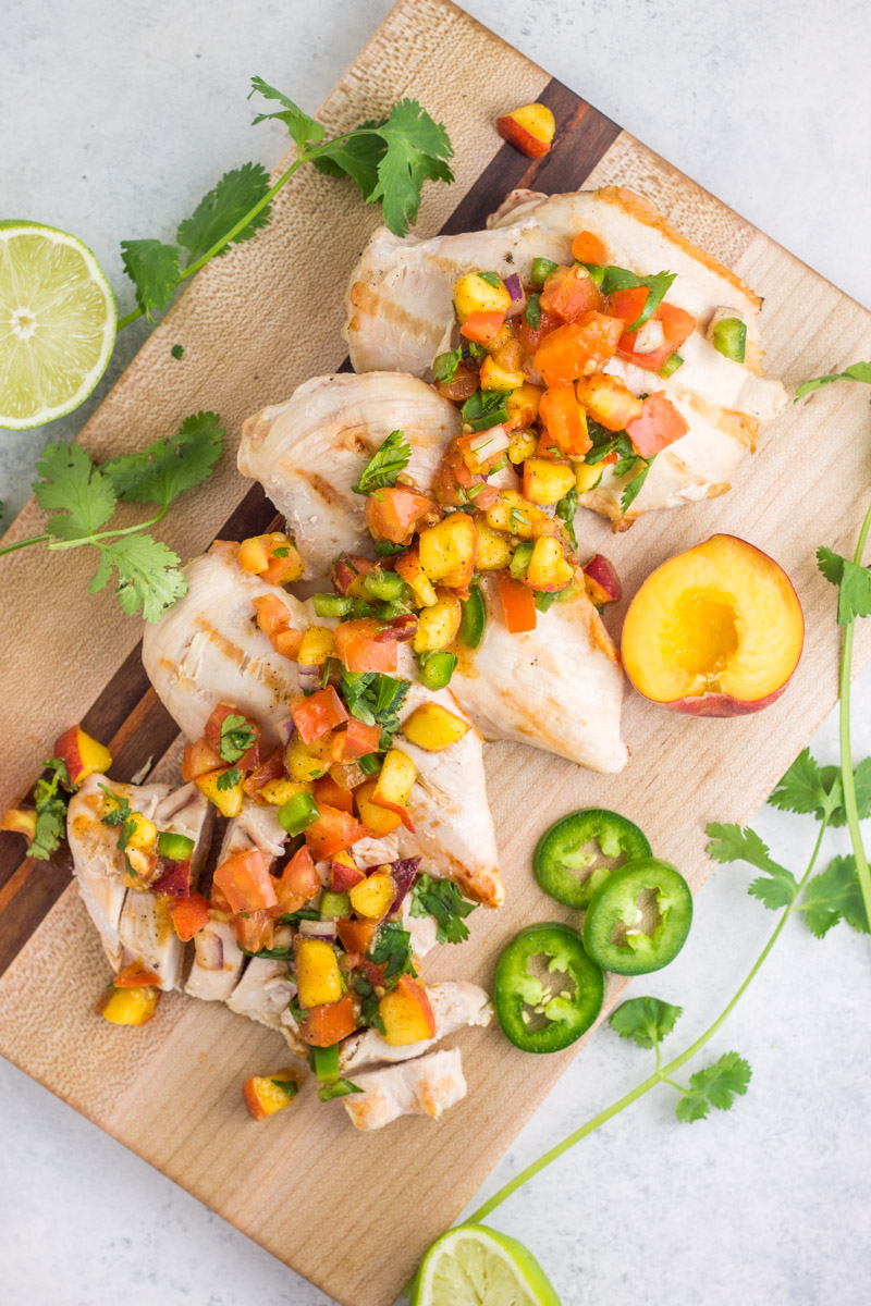 Easy summer dish! Grilled chicken with jalapeño peach salsa is a simple, healthy way to serve chicken breasts with some major flavor. Paleo and Whole30